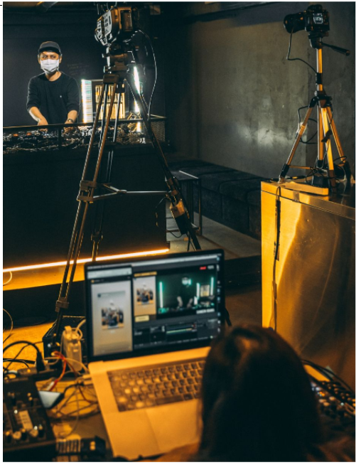 A live streaming studio set up with tripods, cameras, host and editor. Photo by Heshan Perera on Unsplash